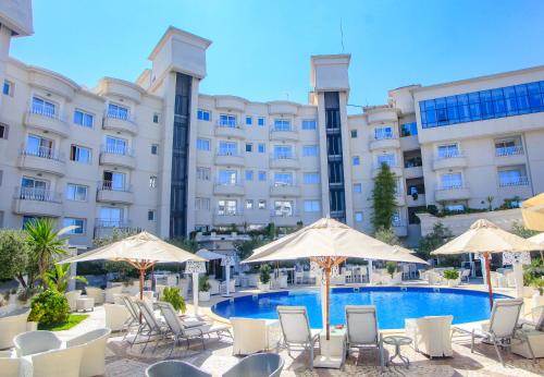 un hotel con piscina, sillas y sombrillas en Tunis Grand Hotel, en Túnez