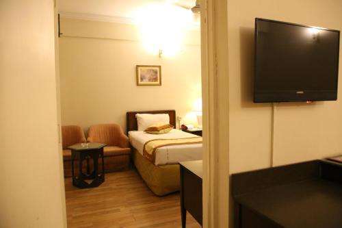 a hotel room with a bed and a flat screen tv at Carlton Tower Hotel Lahore in Lahore
