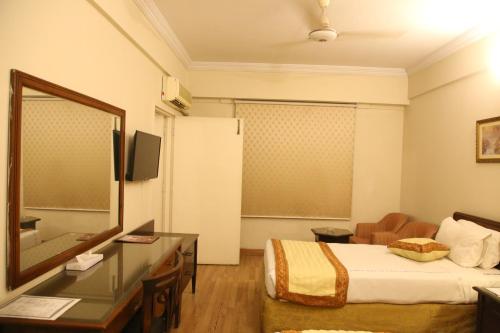 a hotel room with a bed and a desk and a mirror at Carlton Tower Hotel Lahore in Lahore