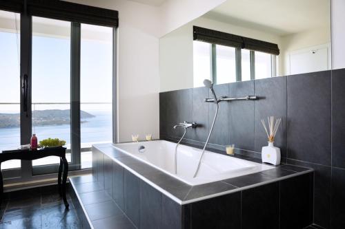 a bath tub in a bathroom with large windows at Luxury Villa Dubrovnik Dream with private pool and sea view near the beach in Orasac - Dubrovnik in Zaton