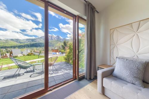 a living room with a couch and a large glass door at Tatra Resort & SPA in Kościelisko