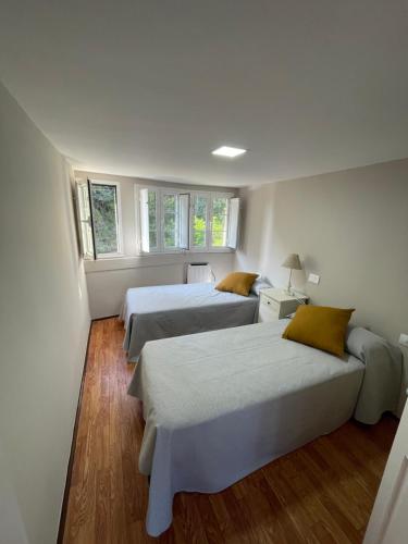 two beds in a room with two windows at Atico El Puerto in Luarca