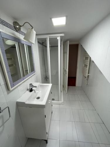 a white bathroom with a sink and a mirror at Atico El Puerto in Luarca