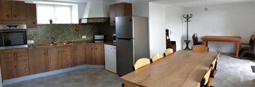 a kitchen with a wooden table and a refrigerator at gîte de la Veillée in Tribehou