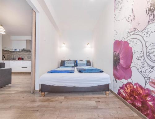ein Schlafzimmer mit einem Bett mit einem Blumenbild an der Wand in der Unterkunft SANDRA APARTMENT CLOSE TO CHAIN BRIDGE in Budapest