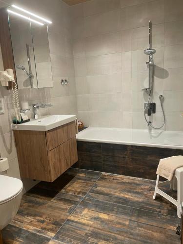 a bathroom with a tub and a sink and a toilet at Hotel Restaurant Neu Meran in Bad Reichenhall