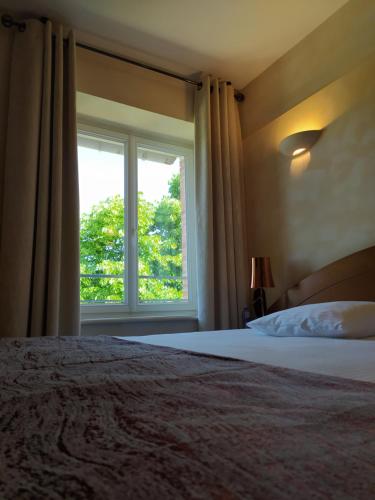 a bedroom with a bed and a large window at Auberge Du Roua in Argelès-sur-Mer