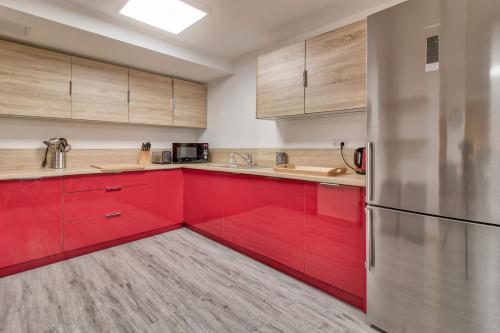 a kitchen with red cabinets and a refrigerator at À 80m des pistes, bel appartement pour 15 in Génos