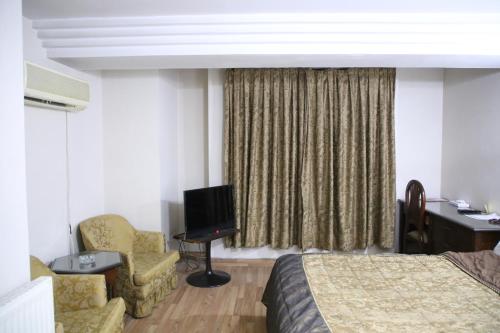 a hotel room with a bed and a chair and a television at Carlton Tower Hotel Lahore in Lahore