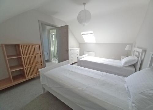 a white bedroom with two beds and a mirror at Beachside Avenue Holiday Home No 15 by Trident Holiday Homes in Courtown