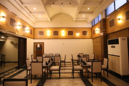 a restaurant with tables and chairs in a room at Carlton Tower Hotel Lahore in Lahore