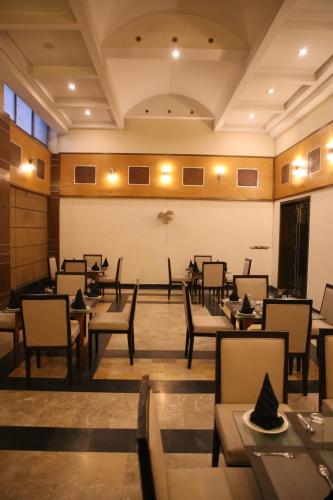 a restaurant with tables and chairs in a room at Carlton Tower Hotel Lahore in Lahore