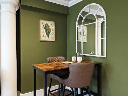comedor con paredes verdes y mesa y sillas de madera en The Botanist's Hideout - Luxury Retreat with Parking, en York