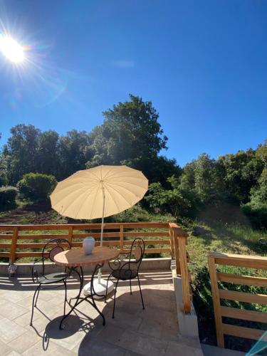 a table and chairs with an umbrella on a deck at B&B La Fucinaia Pet Friendly Adults only in Campiglia Marittima