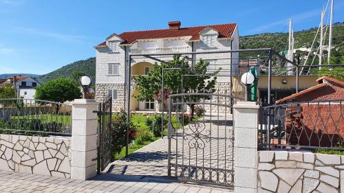 ein Haus mit einem Tor vor einem Haus in der Unterkunft Apartments Lorena in Mokošica