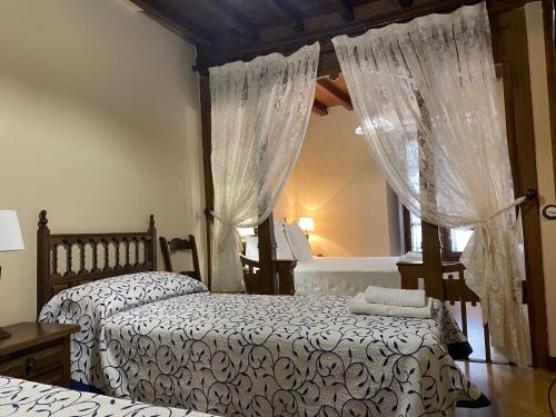 a bedroom with two beds and a window with curtains at Hotel rural Rinconada de las Arribes in Aldeadávila de la Ribera