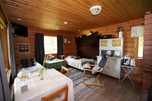 Sala de estar de una cabaña de madera con mesa y cocina en Kinkamon Pirtti, en Keuruu