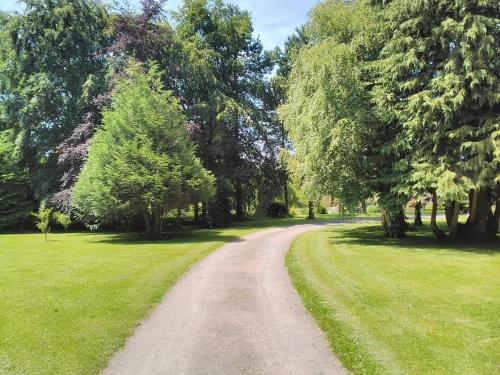 un chemin de terre dans un parc planté d'arbres et d'herbe dans l'établissement La Maison Periot, à Trévières