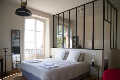 a bedroom with a bed with white sheets and windows at Le Domaine de Dony in Balbins