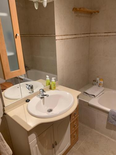a bathroom with a sink and a mirror and a tub at Apartamento con jardín y piscina en el faro de calaburras in Mijas Costa
