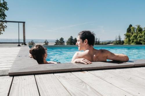 een man en een vrouw die in een zwembad liggen bij Le Domaine de Dony in Balbins