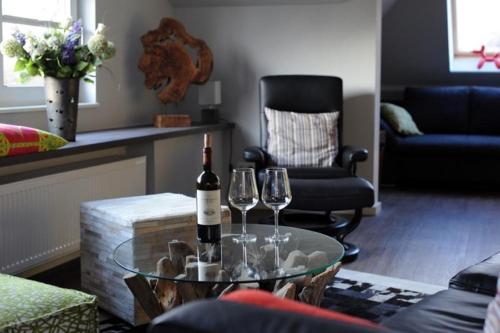 a living room with a glass table with two wine glasses at Villa Zwölf in Soltau