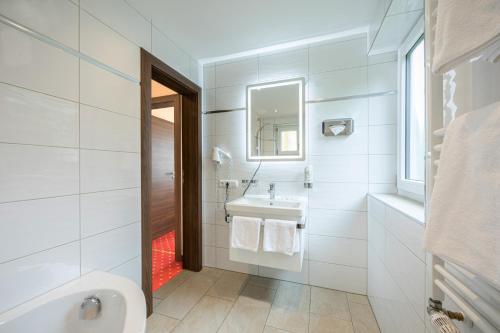 a white bathroom with a sink and a mirror at Hotel AlpinaRos in Berchtesgaden