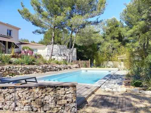 a swimming pool in a yard with a stone wall at Studio d'Hôtes les Libellules in Castelnau-le-Lez