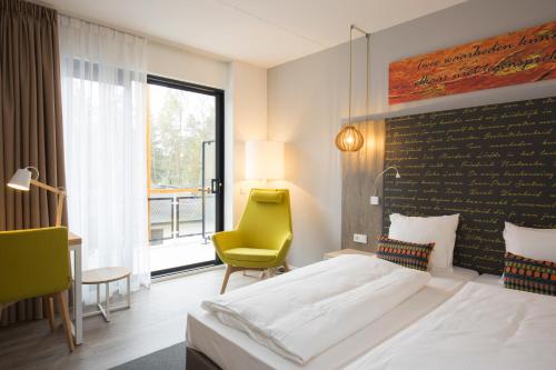 une chambre d'hôtel avec un lit et une chaise jaune dans l'établissement Landgoed ISVW, à Leusden