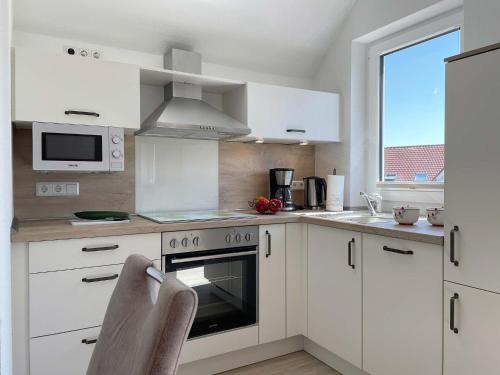 a kitchen with white cabinets and a stove top oven at Haus Nordseekrabbe in Greetsiel