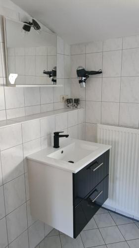 a white bathroom with a sink and a mirror at Pension "Am Fischerweg" in Heringsdorf