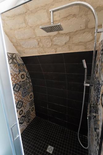 a bathroom with a shower with black tiles at Bed and Breakfast Terra del Sole Ibla in Ragusa