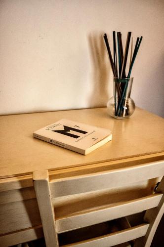 a book on a wooden table with a vase of sticks at Il Casale di David in Pontedera