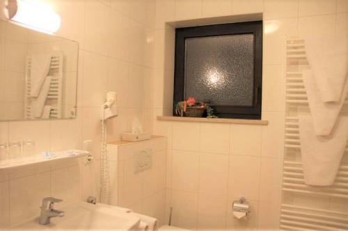 a bathroom with a sink and a toilet and a window at Alpenhotel Brennerbascht in Bischofswiesen