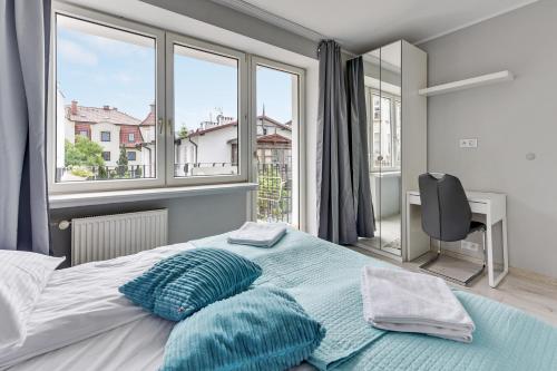 a bedroom with a bed and a desk and windows at Grand Apartments - Silver Sands Sopot Apartment in Sopot