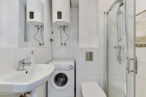 a white bathroom with a washing machine and a sink at Grand Apartments - Silver Sands Sopot Apartment in Sopot