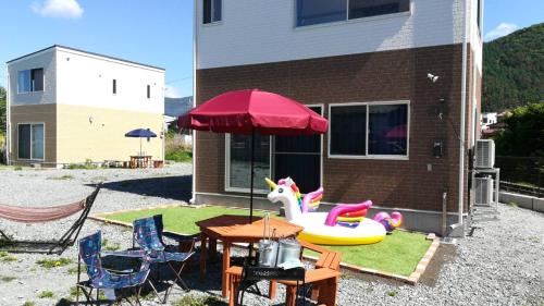 a patio with a table and an umbrella and a toy unicorn at Private House Sakura in Fujikawaguchiko