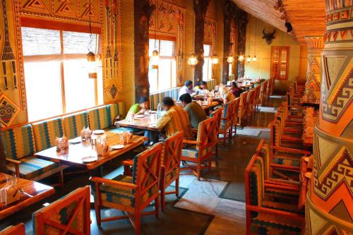 a dining room with people sitting at tables in a restaurant at Ramoji Film City- Tara Comfort Hotel in Pedda Ambarpet