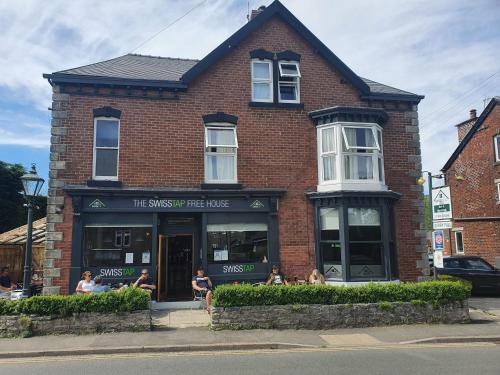 a brick building with people sitting outside of it at Swiss Guest House in Castleton