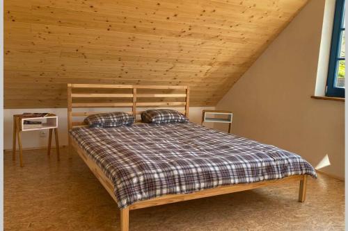 uma cama num quarto com tecto em madeira em Chalupa Vojtěchov 60 em Hvozd