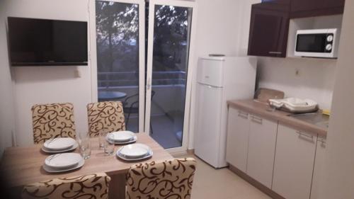 a kitchen with a wooden table and chairs and a kitchen with a counter at Apartments VRSI 4494 in Vrsi