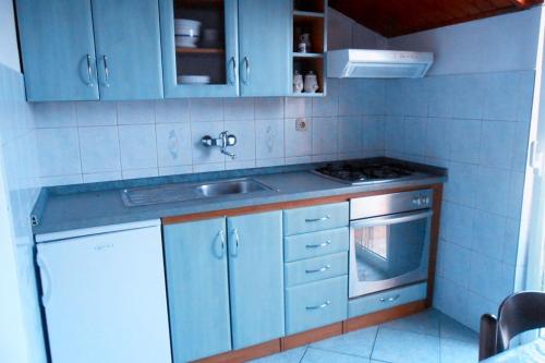 eine Küche mit blauen Schränken, einer Spüle und einem Herd in der Unterkunft Apartments BISERKA (4232) in Poljana