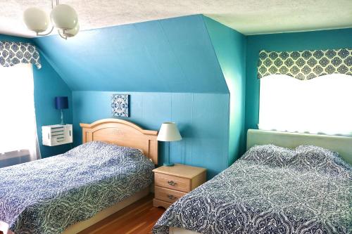 a bedroom with two beds and blue walls at Les Petits Trésors in Coaticook