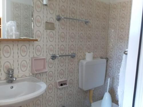 een badkamer met een wastafel, een toilet en een spiegel bij Hotel Gino in Noli