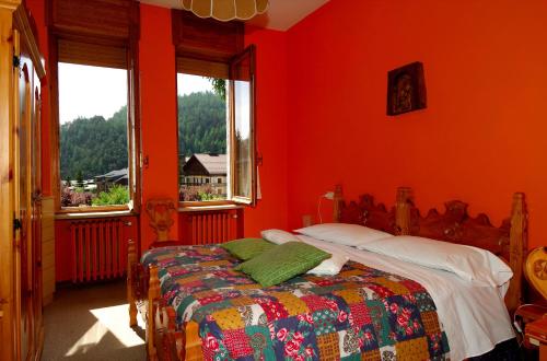 a red bedroom with a bed and two windows at Villa Myosotis in Bardonecchia