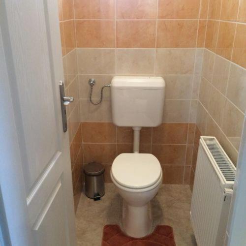 a bathroom with a toilet in a tiled room at Báró Berg Apartman2 in Kapuvár