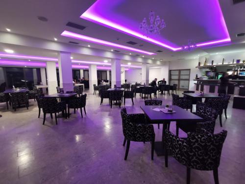 Mali ZvornikにあるHotel Royal Drinaのダイニングルーム(テーブル、椅子、紫色の照明付)