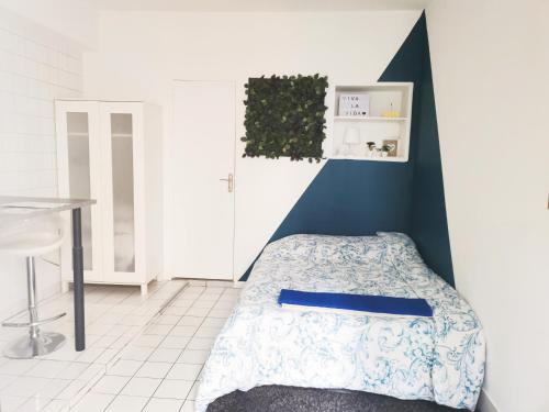 a bedroom with a bed and a blue accent wall at #5 Studio à proximité de Paris in Bagnolet