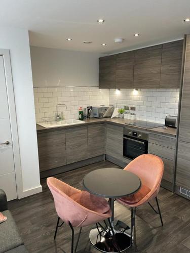 a kitchen with a table and two pink chairs at The Whyte House in Sheffield