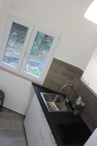 a kitchen with a sink and two windows at Casinhas da Lu in Geres